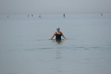 Woman with swim cap and goggles up to waist in water