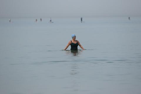 Woman with swim cap and goggles up to waist in water