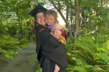 Roberta Watts in graduation regalia holds one of her children