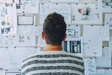 Man studies pinboard full of papers