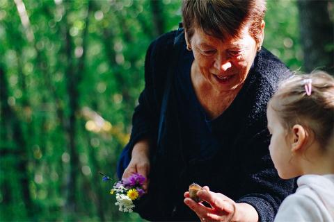 Older woman holding shows stone to small child.