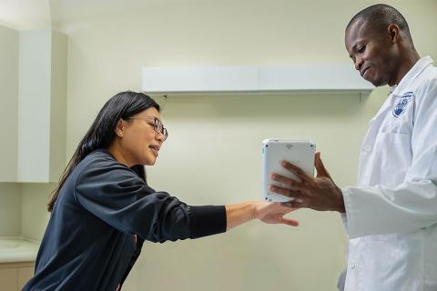 Two people, one in lab coat, consulting over a tablet