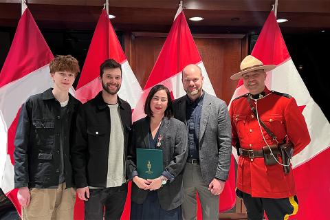 Meaghan accepts the Coronation Award with her family and an RCMP officer