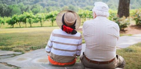 Older couple sit on bench overlooking field